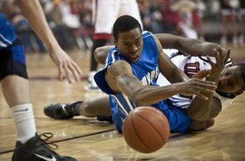 joueurs de basket se disputant le gain du ballon au sol avec hargne