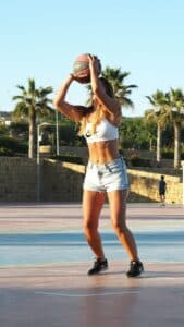 Jeune femme au corps musclé jouant au basketball dans une tenue dzcontractée